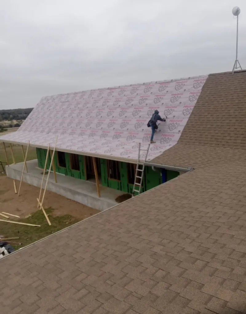 Worker preparing underlayment for a metal roof installation in Louisville